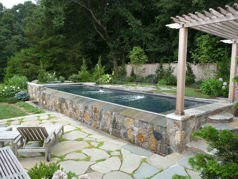Exemple d'une piscine arrière bord de mer rectangle avec un point d'eau et des pavés en pierre naturelle.