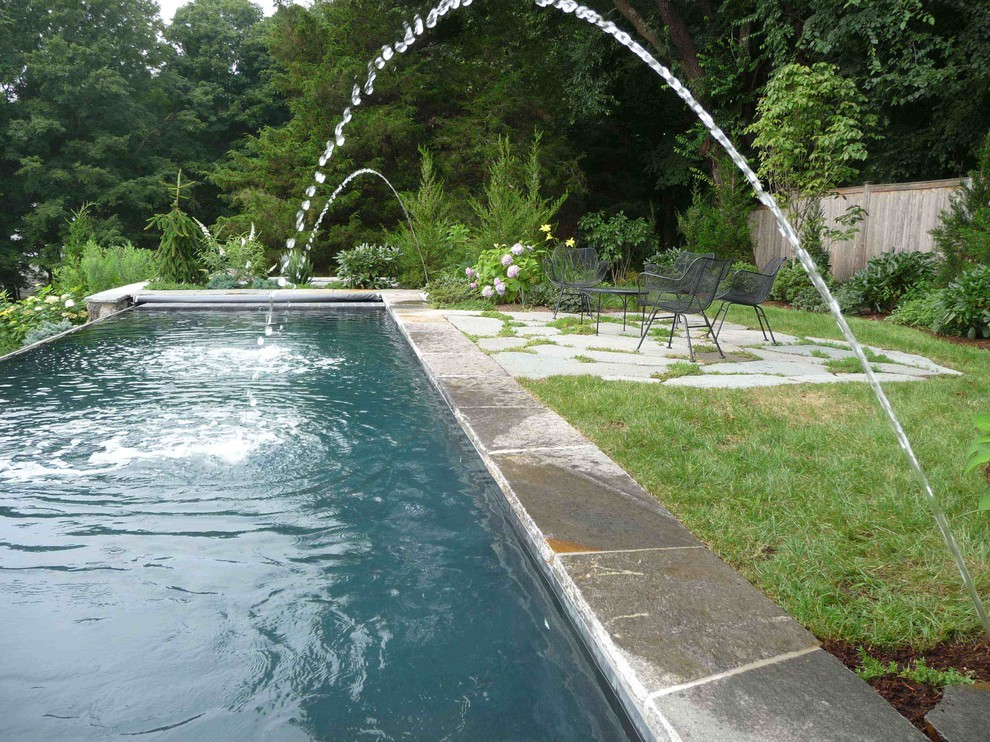 Diseño de piscina con fuente costera rectangular en patio trasero con adoquines de piedra natural