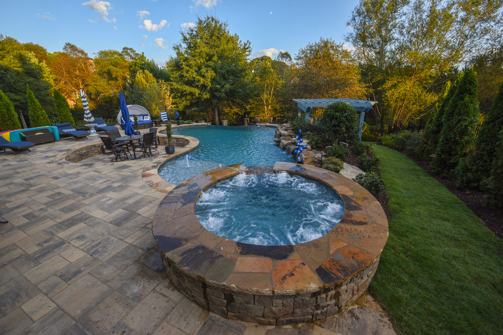 Inspiration for an expansive world-inspired back custom shaped infinity hot tub in Atlanta with concrete paving.