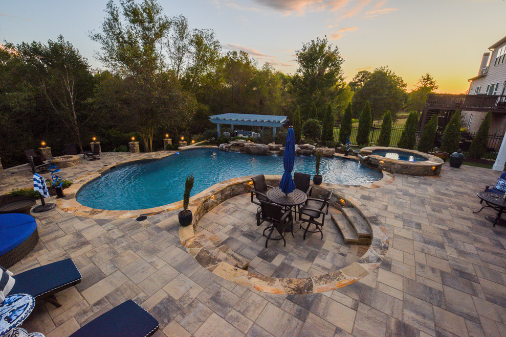 Esempio di un'ampia piscina a sfioro infinito tropicale personalizzata dietro casa con una vasca idromassaggio e pavimentazioni in cemento