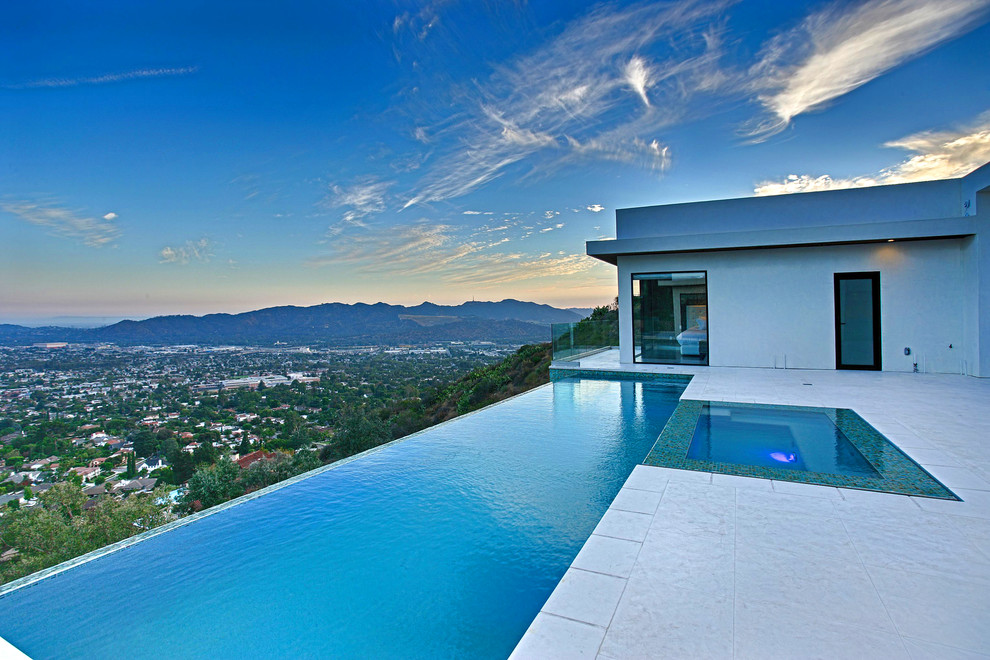 Large minimalist backyard concrete and rectangular infinity hot tub photo in Los Angeles
