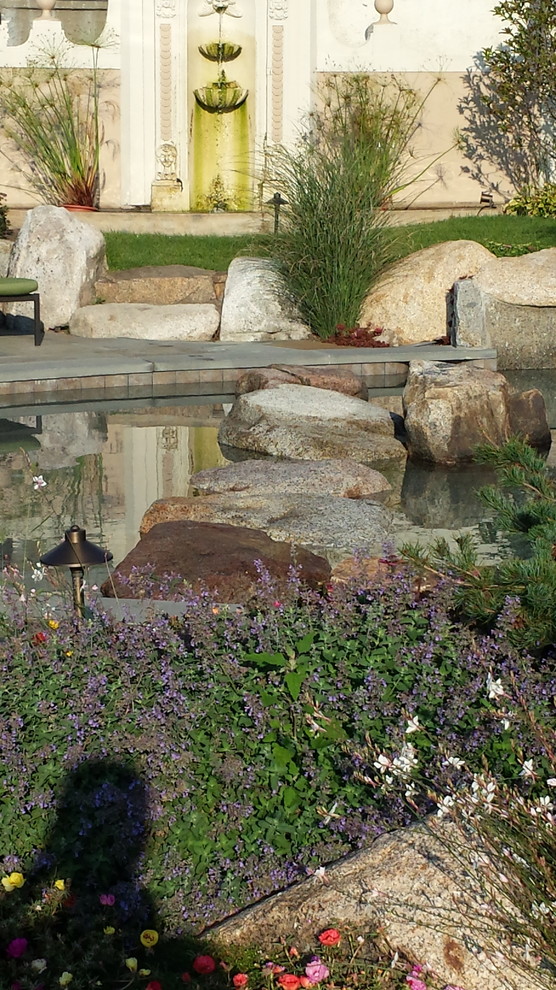 Imagen de jardín marinero extra grande en patio lateral con fuente y adoquines de piedra natural