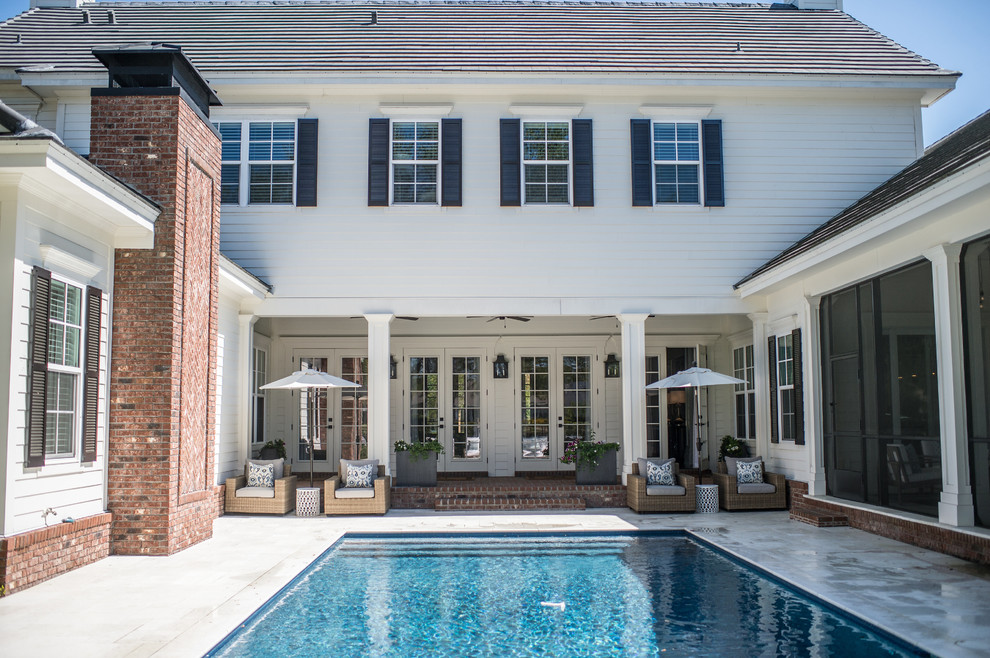 Ejemplo de piscina alargada clásica renovada grande rectangular en patio trasero con adoquines de piedra natural