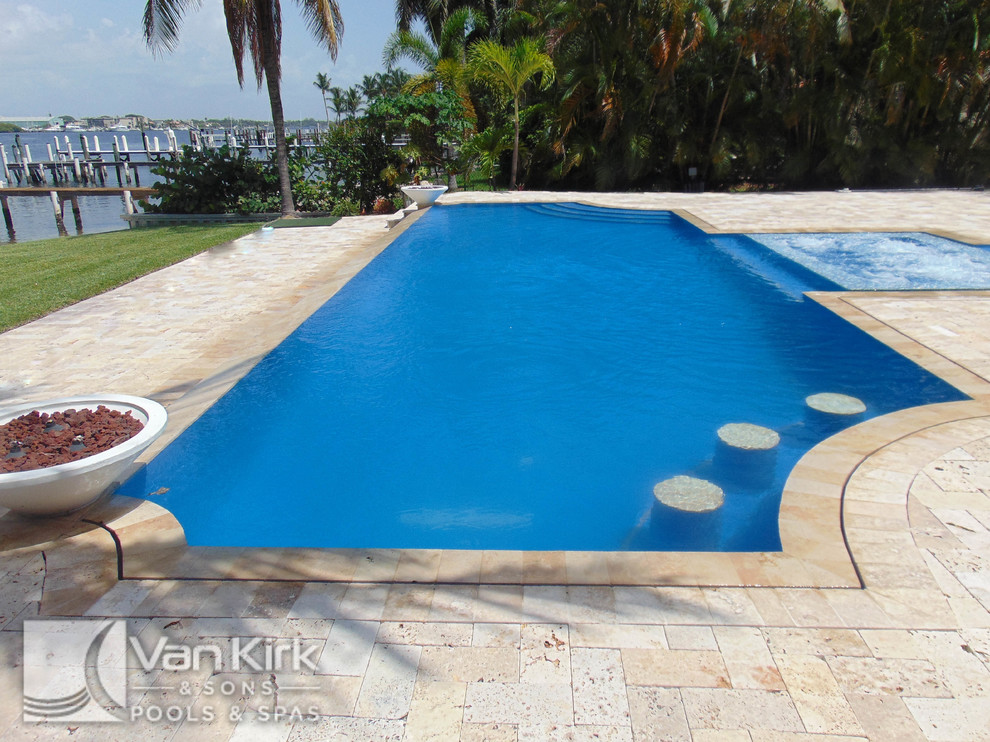 Large backyard custom-shaped infinity hot tub photo in Miami