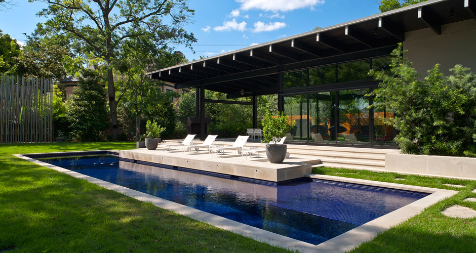 Foto de casa de la piscina y piscina actual de tamaño medio rectangular en patio trasero con adoquines de hormigón