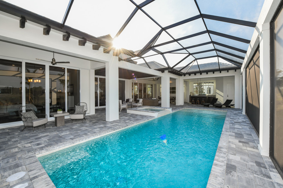 Diseño de piscina alargada tradicional renovada grande rectangular en patio trasero con adoquines de piedra natural