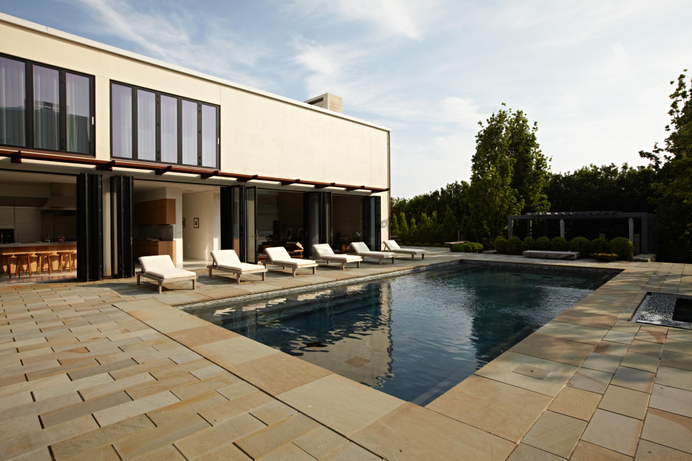 Ejemplo de casa de la piscina y piscina alargada moderna rectangular en patio trasero con losas de hormigón