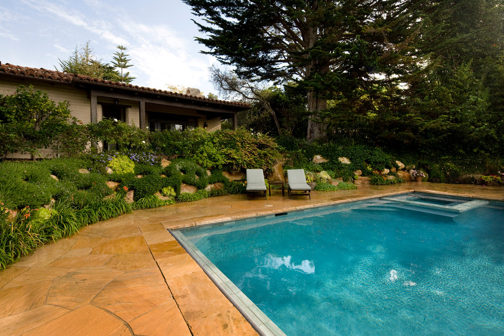 This is an example of a large mediterranean back rectangular infinity swimming pool in Santa Barbara with natural stone paving.