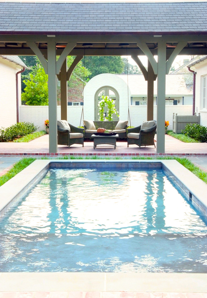 Ejemplo de piscina clásica pequeña rectangular en patio trasero con adoquines de ladrillo