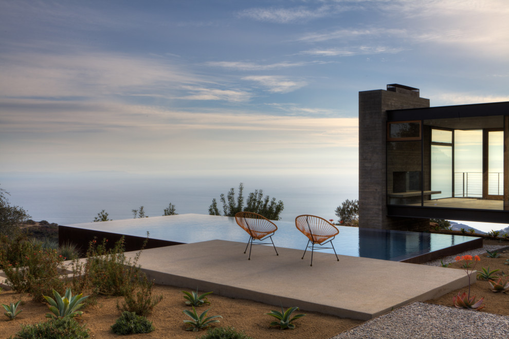 Ispirazione per una piscina a sfioro infinito minimal rettangolare di medie dimensioni e dietro casa con lastre di cemento