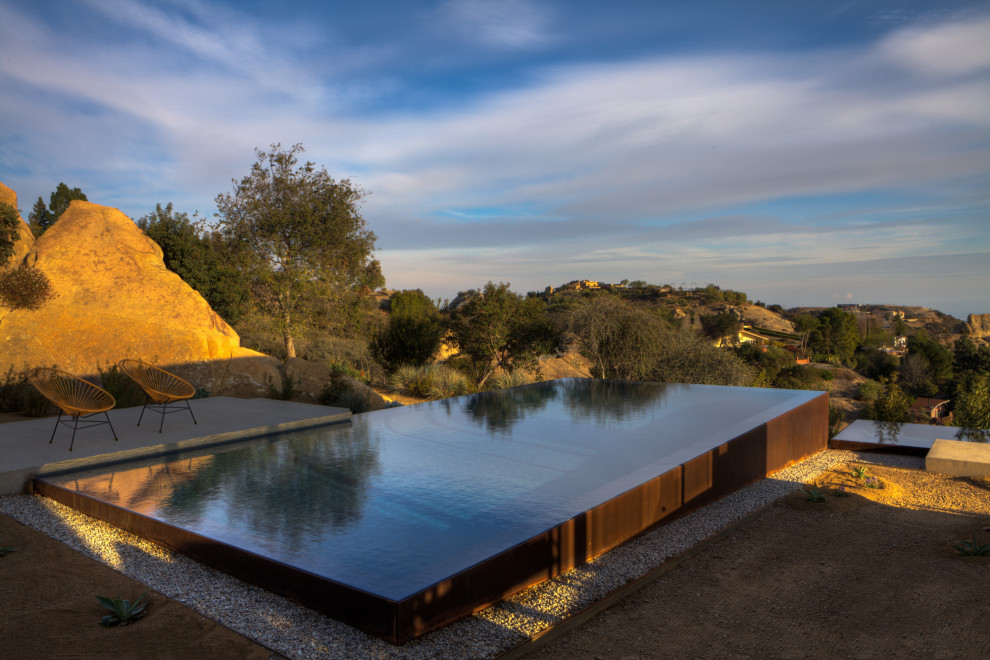 Стильный дизайн: прямоугольный бассейн-инфинити среднего размера на заднем дворе в современном стиле с покрытием из бетонных плит - последний тренд