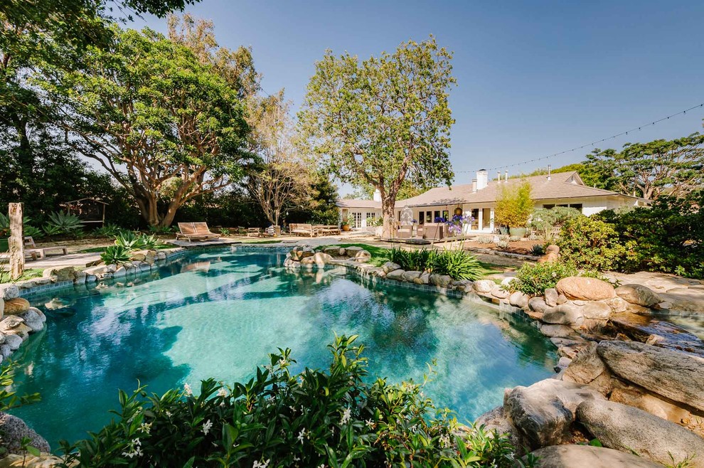 Cette photo montre une très grande piscine naturelle et arrière éclectique sur mesure avec un bain bouillonnant et des pavés en pierre naturelle.