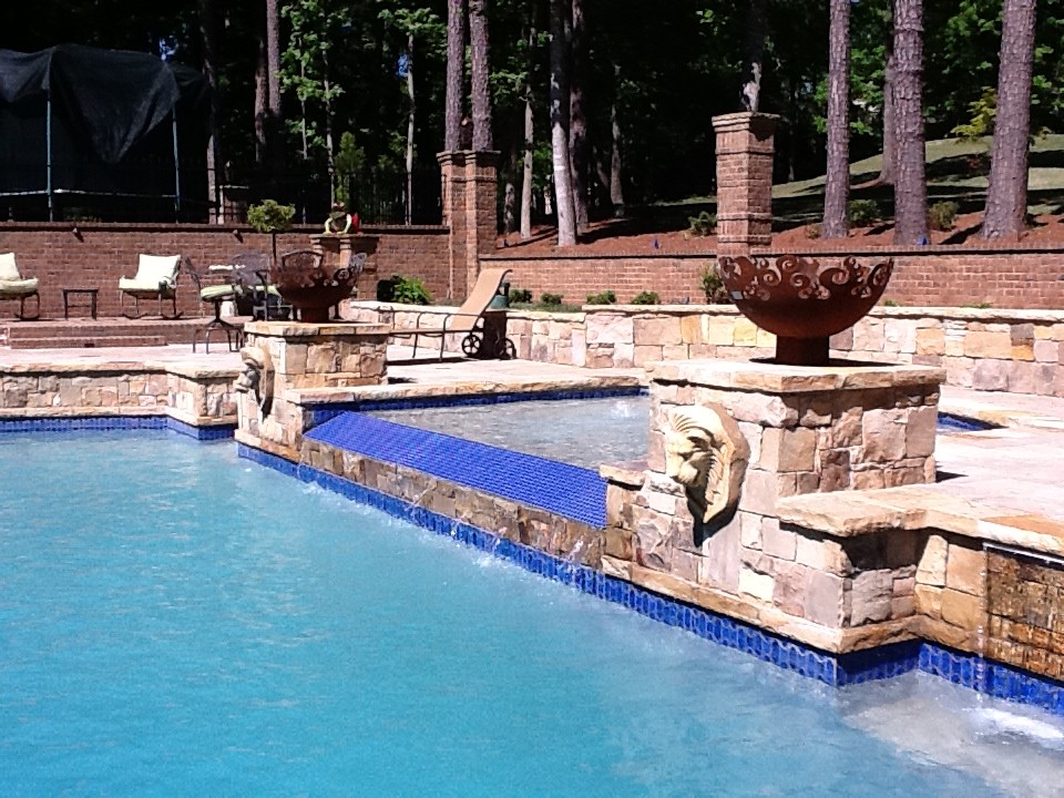 Cette image montre une grande piscine arrière minimaliste rectangle avec un bain bouillonnant et du béton estampé.