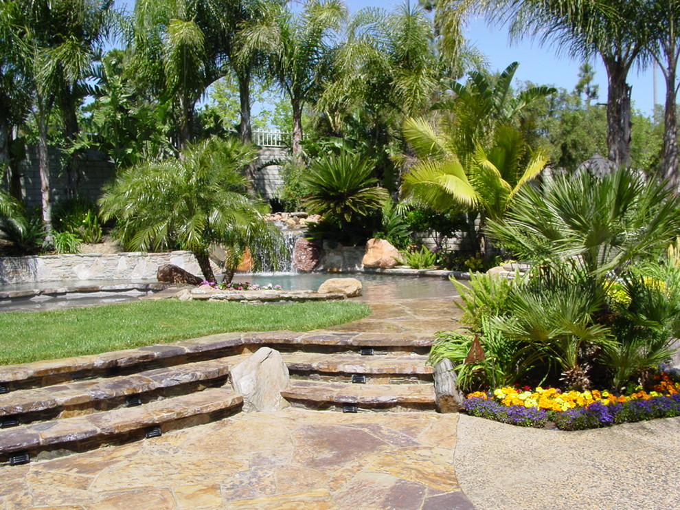 Aménagement d'une piscine naturelle et arrière exotique de taille moyenne et sur mesure avec un point d'eau et des pavés en pierre naturelle.