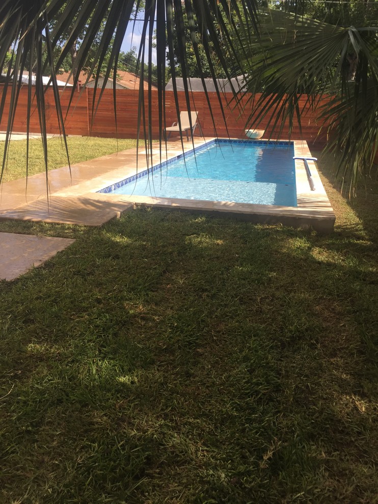 Foto de piscina con fuente alargada actual pequeña rectangular en patio trasero con losas de hormigón
