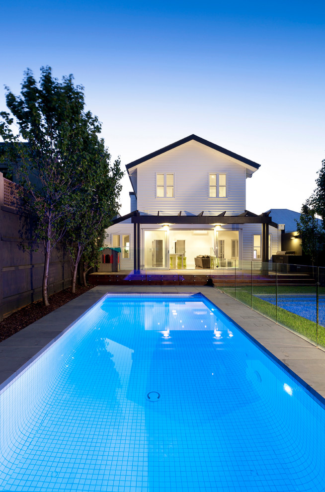 Diseño de piscina alargada clásica de tamaño medio rectangular en patio trasero con suelo de baldosas
