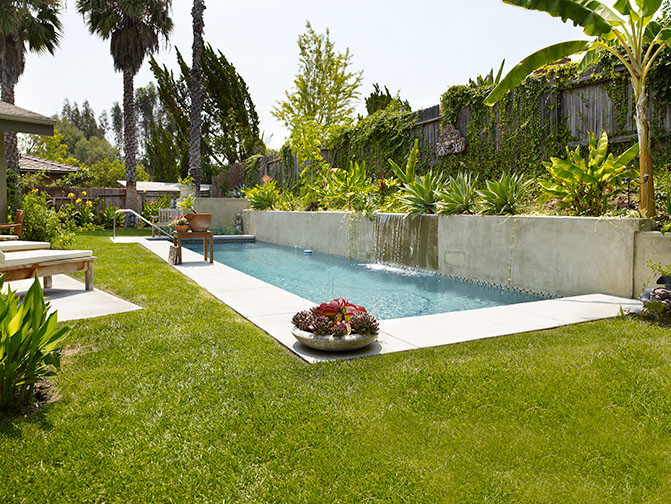 Diseño de piscina de estilo zen grande rectangular en patio trasero con losas de hormigón