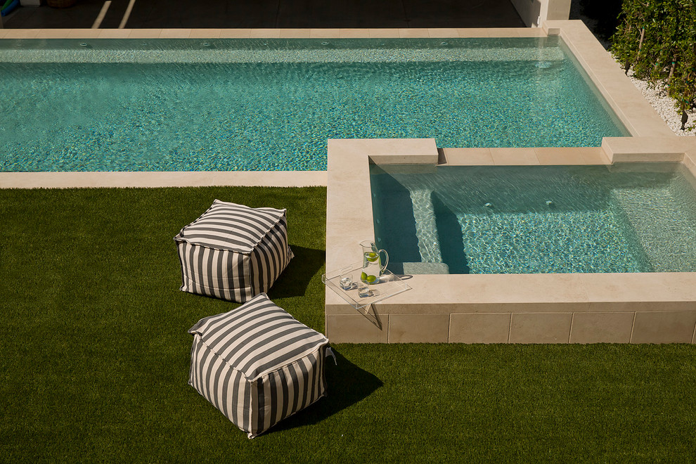 Esempio di una piscina a sfioro infinito stile marinaro rettangolare di medie dimensioni e dietro casa con una dépendance a bordo piscina e pavimentazioni in pietra naturale