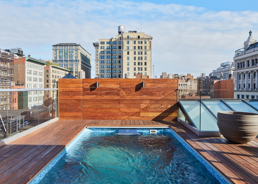 Cette photo montre une grande piscine sur toit tendance rectangle avec une terrasse en bois.