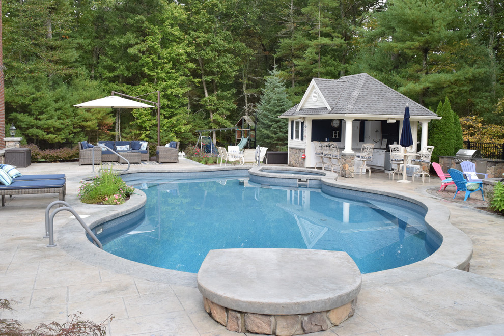 Ejemplo de casa de la piscina y piscina alargada tradicional de tamaño medio tipo riñón en patio trasero con suelo de hormigón estampado