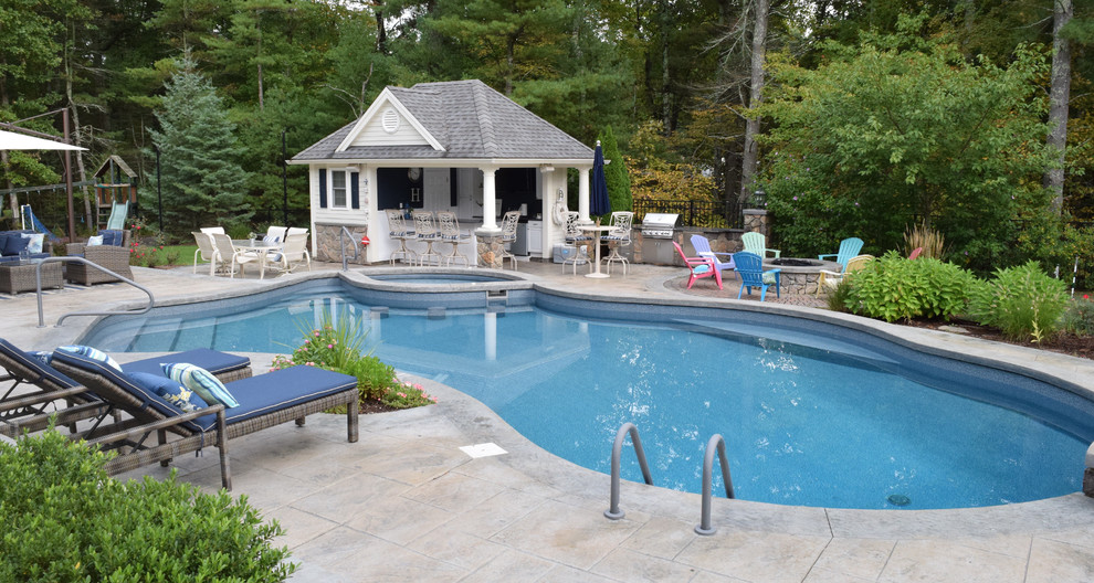 Imagen de casa de la piscina y piscina alargada tradicional de tamaño medio tipo riñón en patio trasero con suelo de hormigón estampado