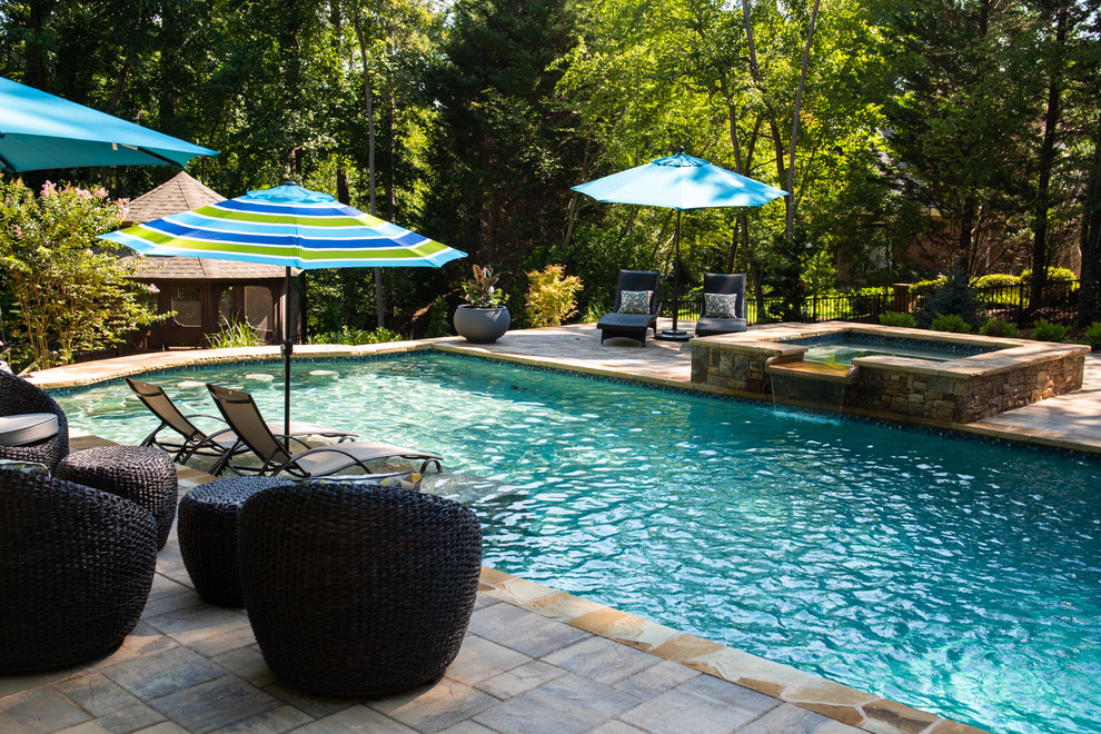 Foto de piscina de estilo americano de tamaño medio rectangular en patio trasero con adoquines de piedra natural