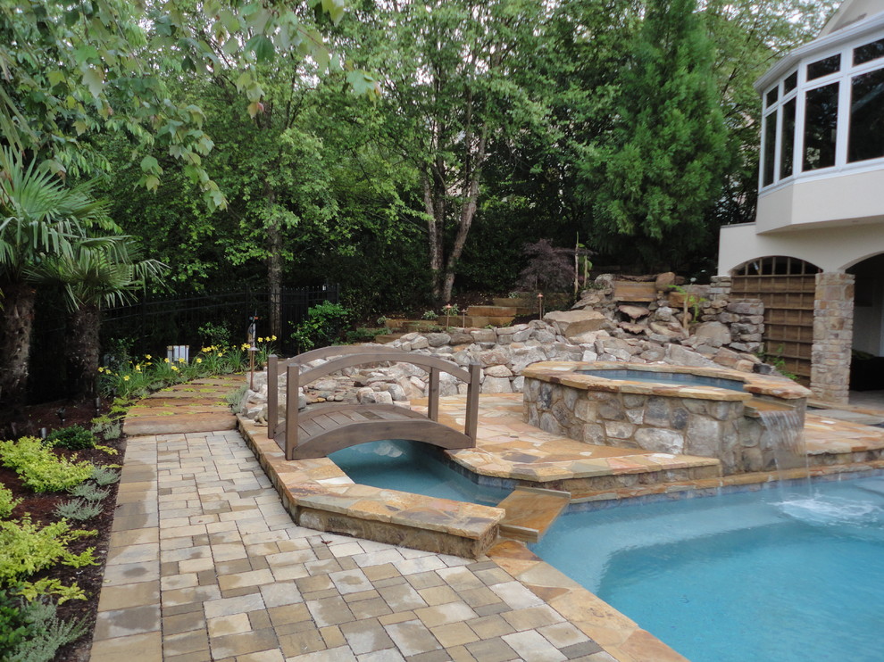 Modelo de piscinas y jacuzzis rústicos de tamaño medio rectangulares en patio trasero con adoquines de hormigón