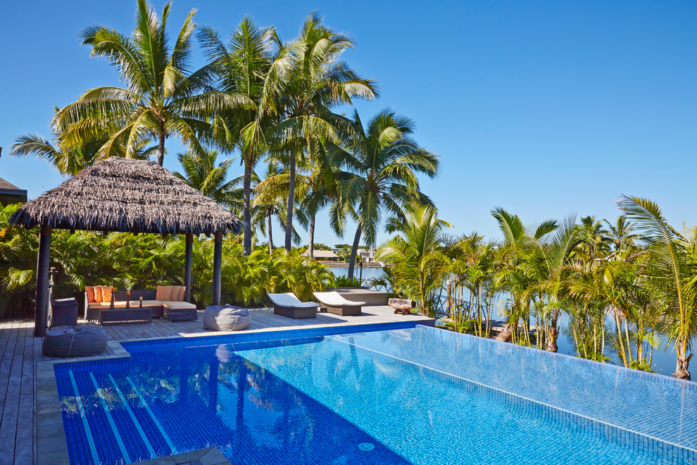 Immagine di una piscina a sfioro infinito tropicale rettangolare con pedane