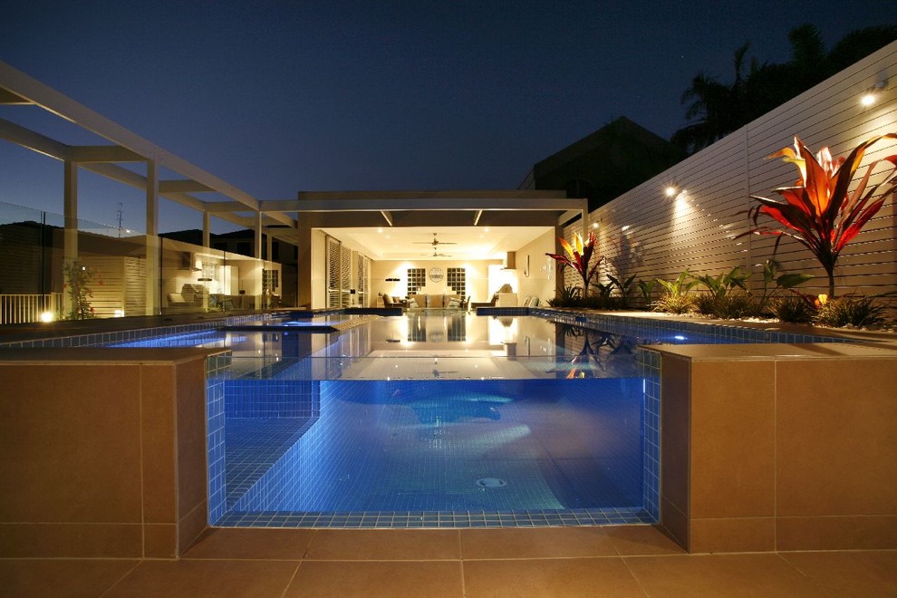 Diseño de casa de la piscina y piscina elevada actual de tamaño medio rectangular en patio trasero con suelo de baldosas