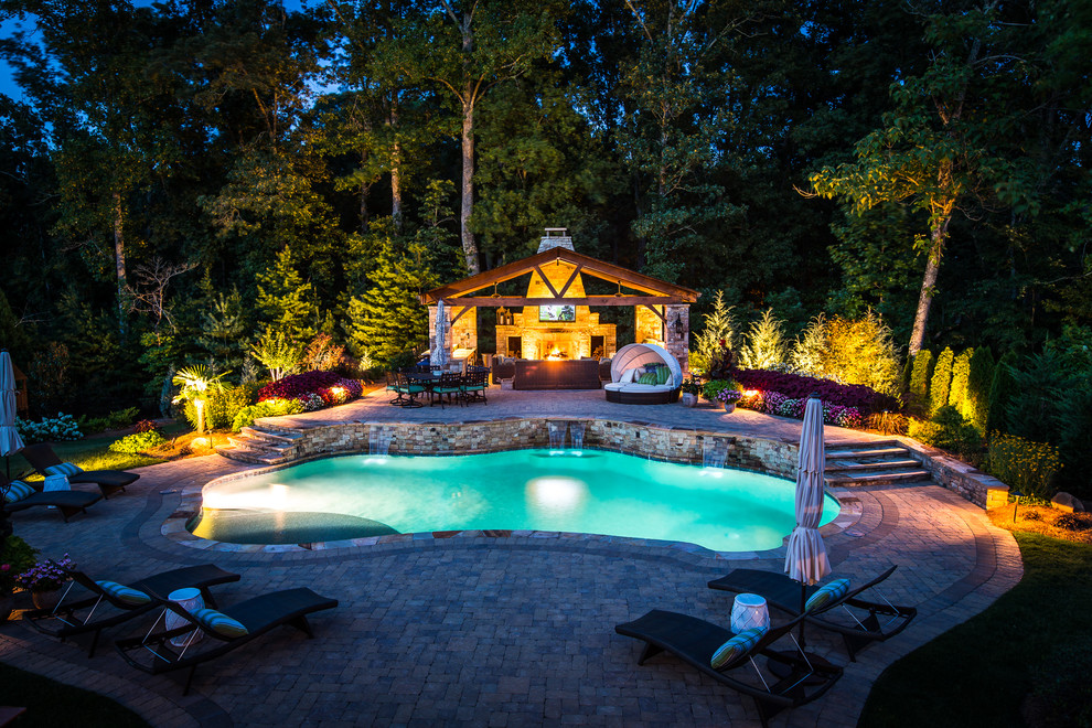 Photo of a large modern back custom shaped swimming pool in Atlanta with a pool house and brick paving.