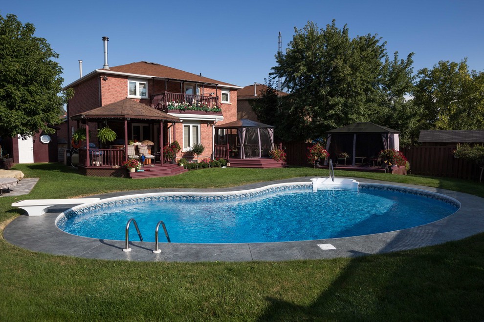 Immagine di una piscina moderna a "C" dietro casa con cemento stampato