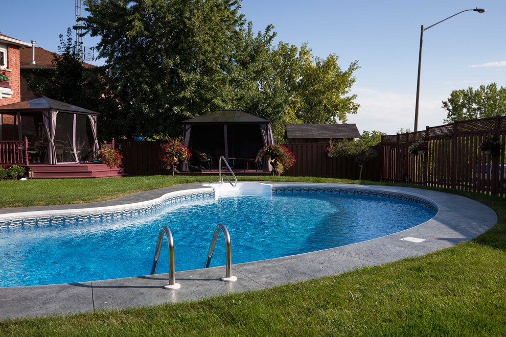 Example of a minimalist backyard stamped concrete and kidney-shaped pool design in Toronto