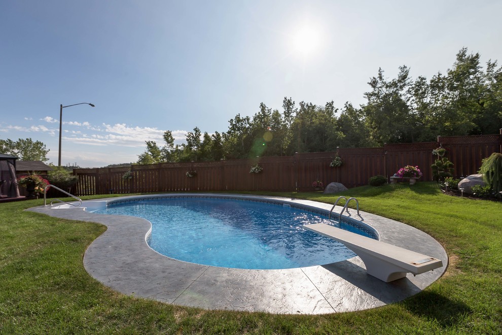 Diseño de piscina minimalista tipo riñón en patio trasero con suelo de hormigón estampado