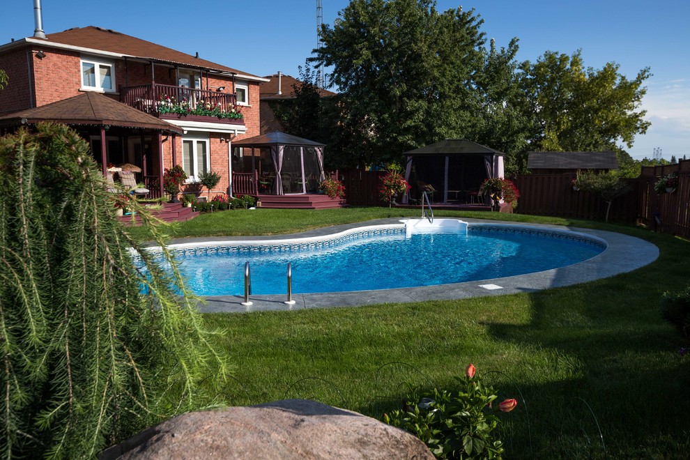 Bild på en funkis njurformad pool på baksidan av huset, med stämplad betong