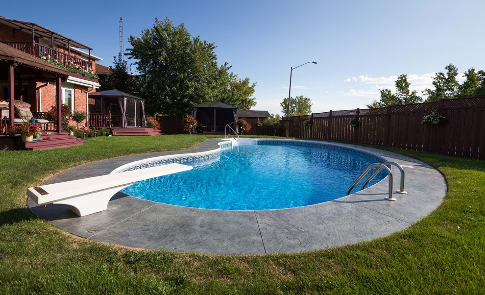 Modern inredning av en njurformad pool på baksidan av huset, med stämplad betong