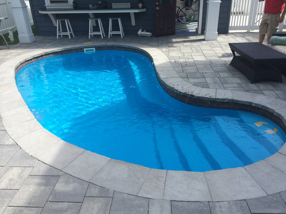 Foto de piscina alargada clásica renovada de tamaño medio tipo riñón en patio trasero con adoquines de hormigón