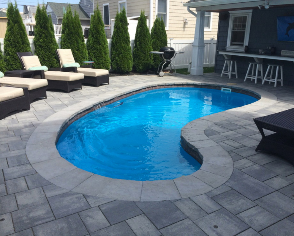 Immagine di una piscina monocorsia classica a "C" di medie dimensioni e dietro casa con pavimentazioni in cemento