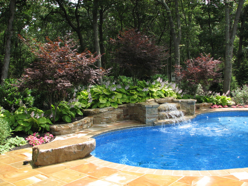 На фото: большой спортивный бассейн в форме фасоли на заднем дворе в классическом стиле с фонтаном