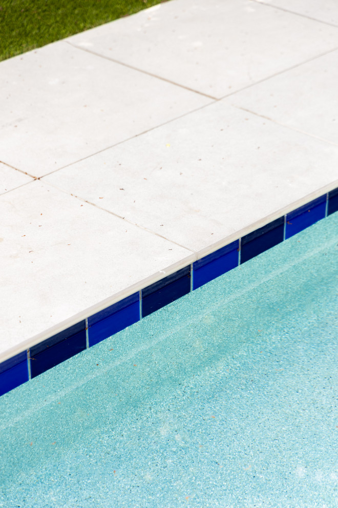 Réalisation d'un grand piscine avec aménagement paysager arrière design avec des pavés en béton.