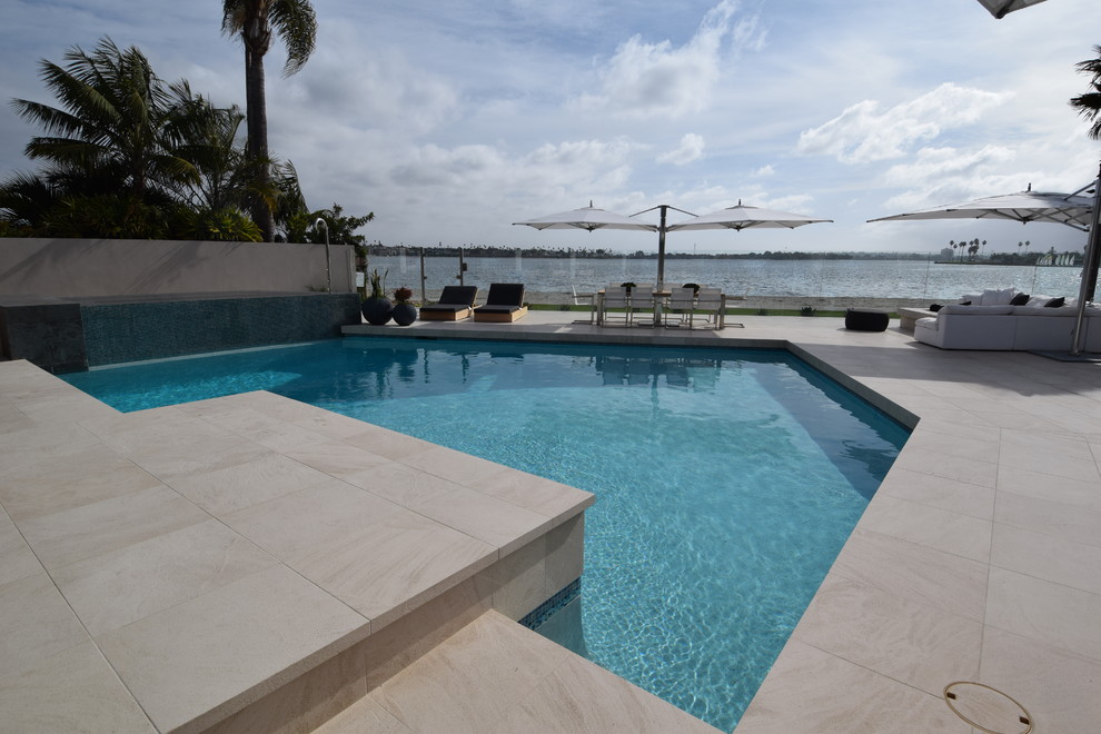 Ejemplo de piscinas y jacuzzis alargados minimalistas de tamaño medio a medida en patio trasero con suelo de baldosas
