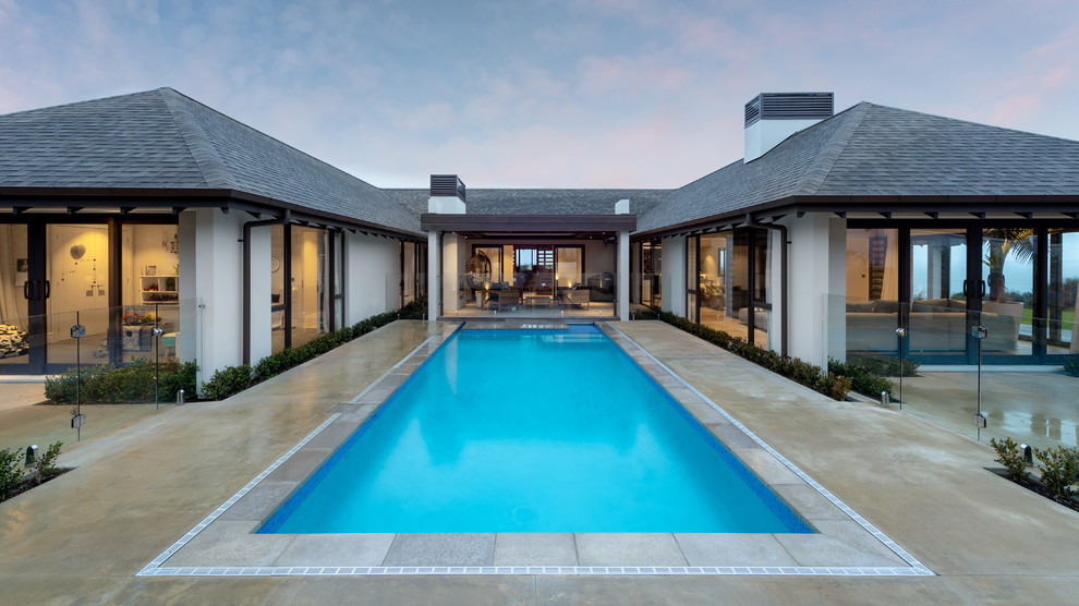 Foto de piscina alargada exótica grande rectangular en patio con losas de hormigón