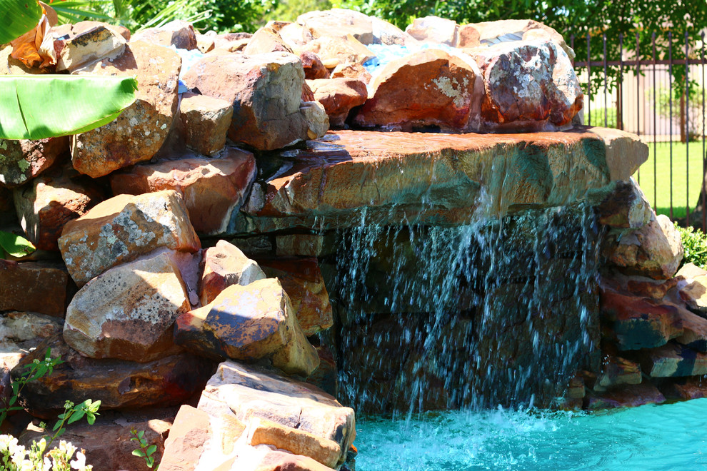 На фото: большой естественный бассейн произвольной формы на заднем дворе в классическом стиле с фонтаном