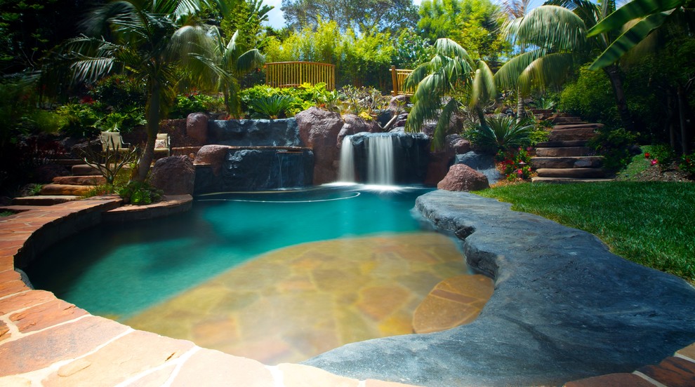 Example of a large island style backyard stone and custom-shaped pool fountain design in San Diego