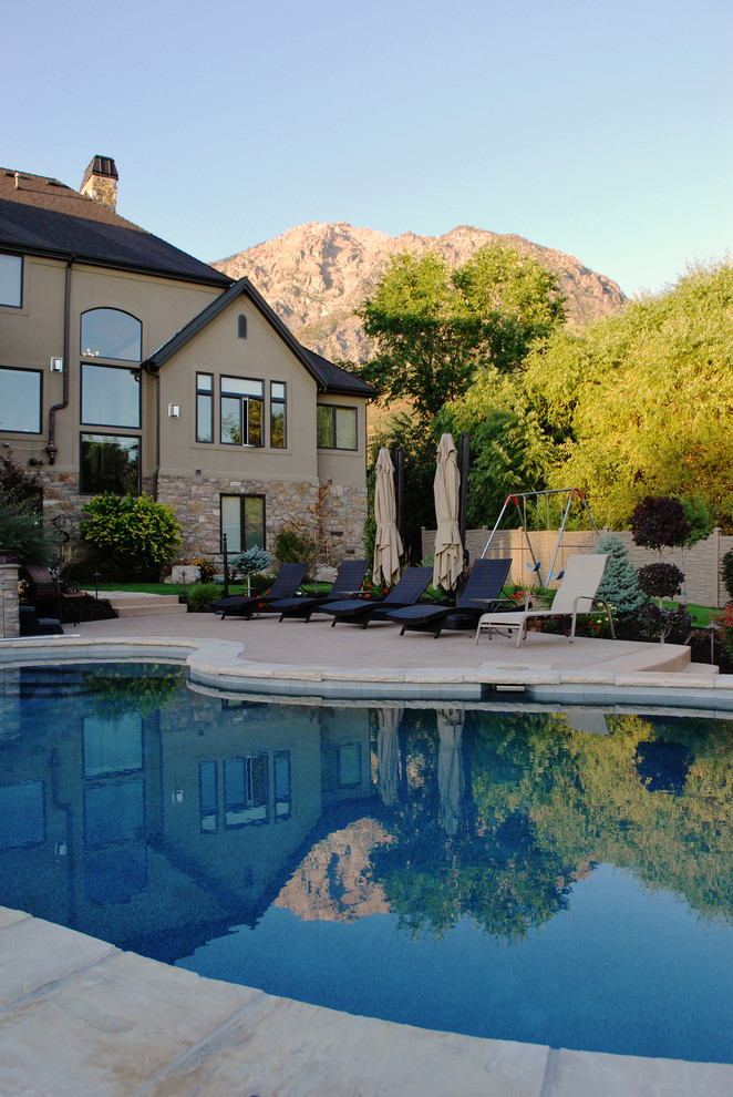 Diseño de piscina tradicional renovada grande tipo riñón en patio trasero con adoquines de piedra natural