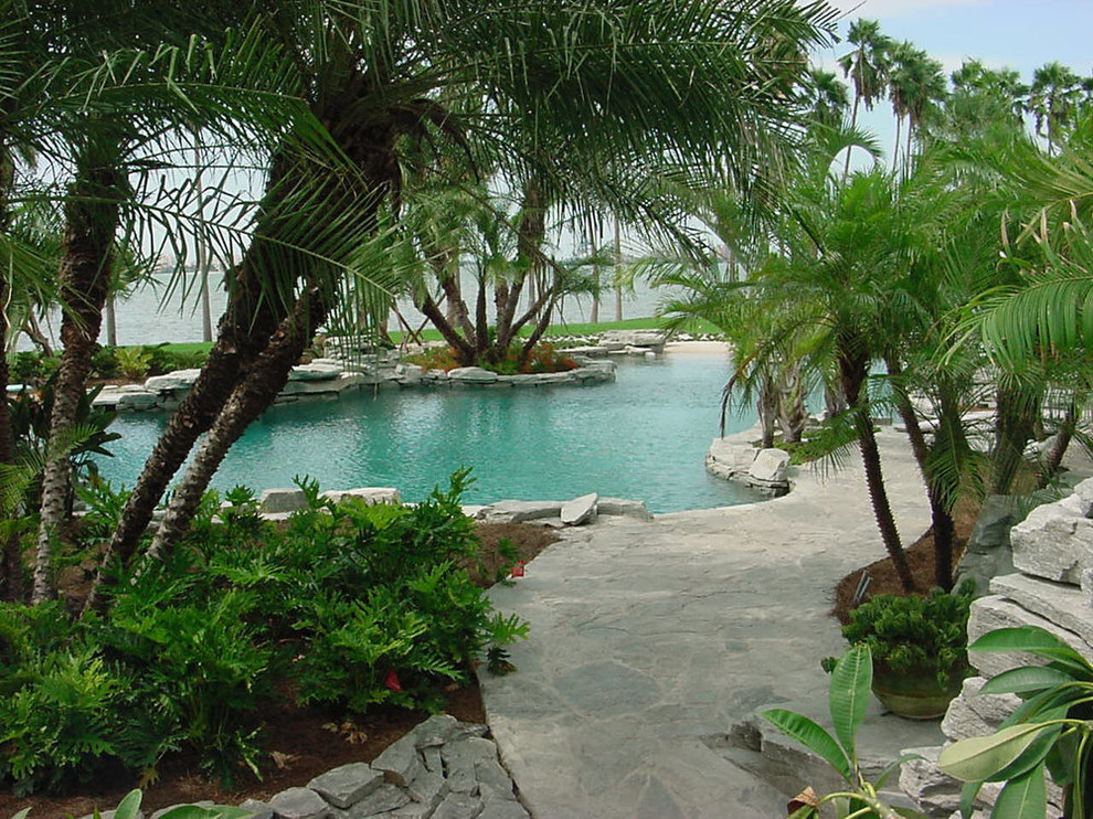 Idées déco pour une grande piscine naturelle et arrière exotique sur mesure avec des pavés en pierre naturelle.