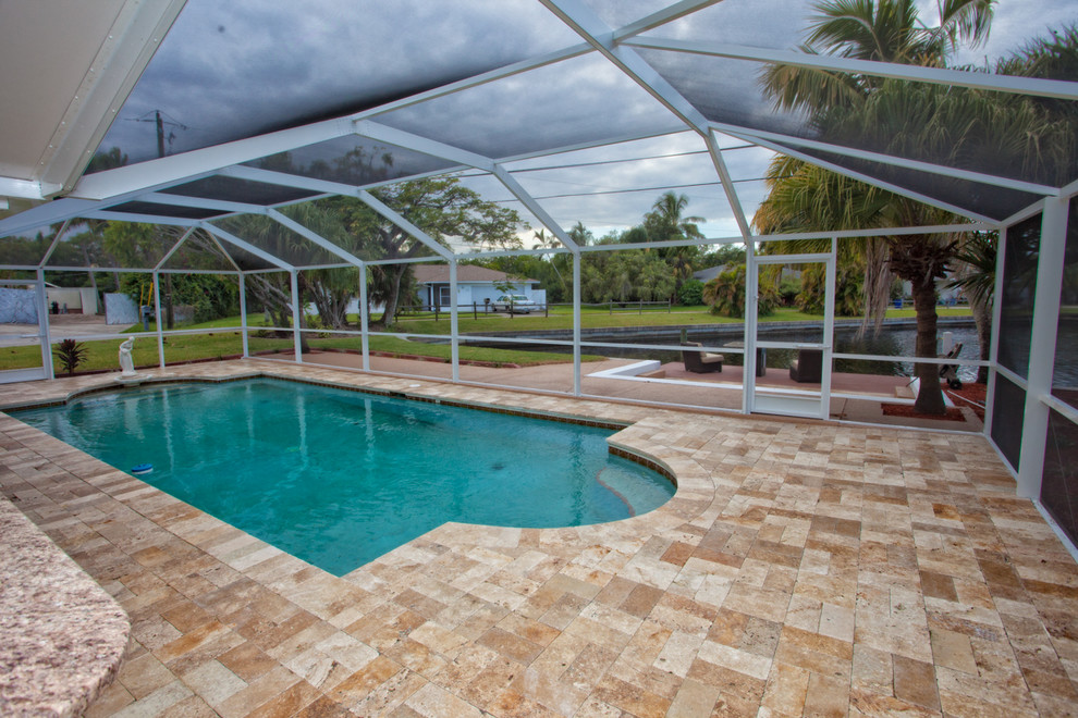 Large elegant backyard tile and custom-shaped pool photo in Miami
