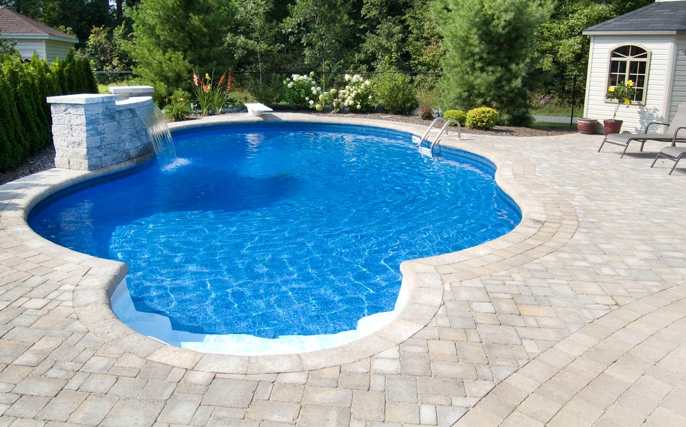 На фото: естественный бассейн произвольной формы на заднем дворе в классическом стиле с мощением клинкерной брусчаткой с