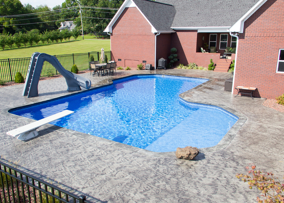 Exempel på en stor klassisk anpassad pool på baksidan av huset, med vattenrutschkana och betongplatta