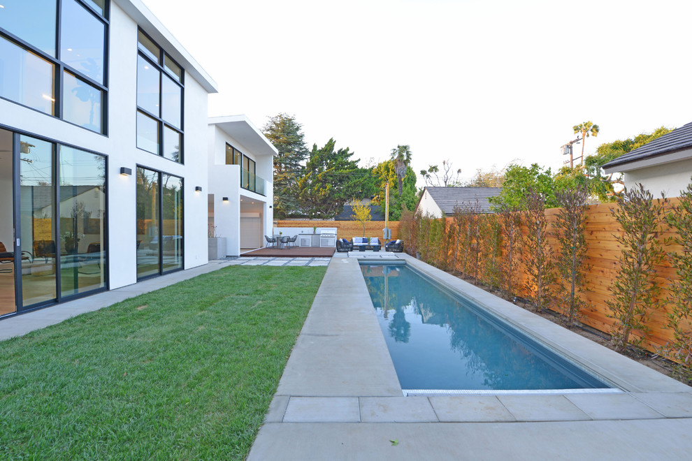 Ejemplo de piscina alargada contemporánea de tamaño medio rectangular en patio trasero con losas de hormigón