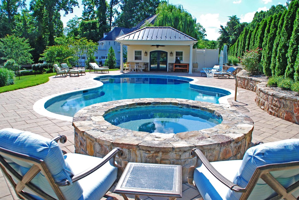 Diseño de piscina tradicional de tamaño medio a medida en patio trasero con adoquines de hormigón